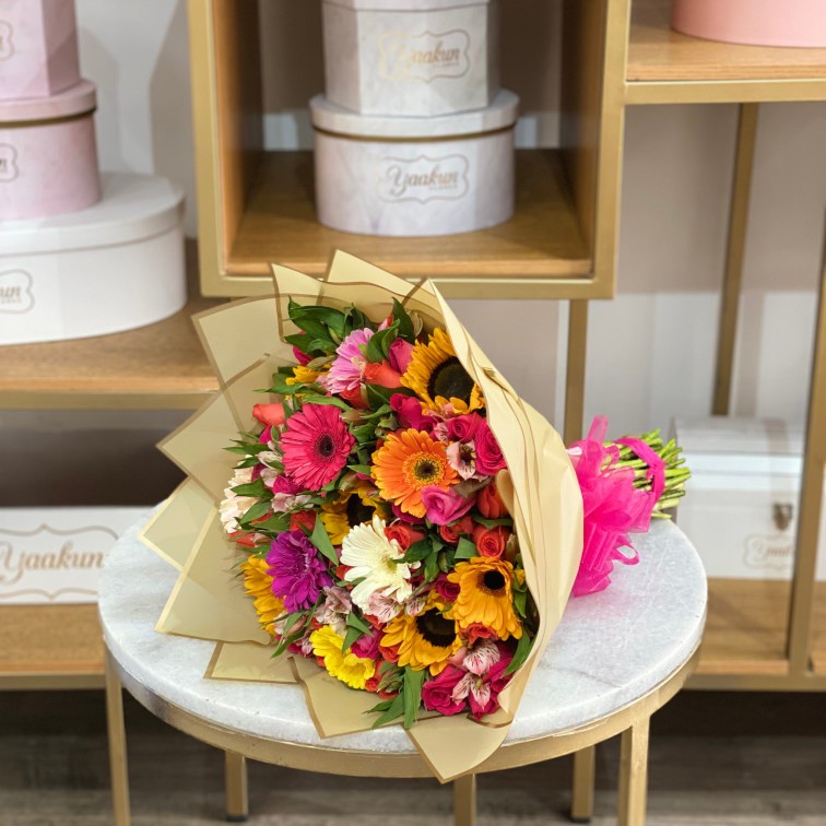 Bouquet coloridos con gerberas, girasoles, rosas y alstromerias en papel coreano