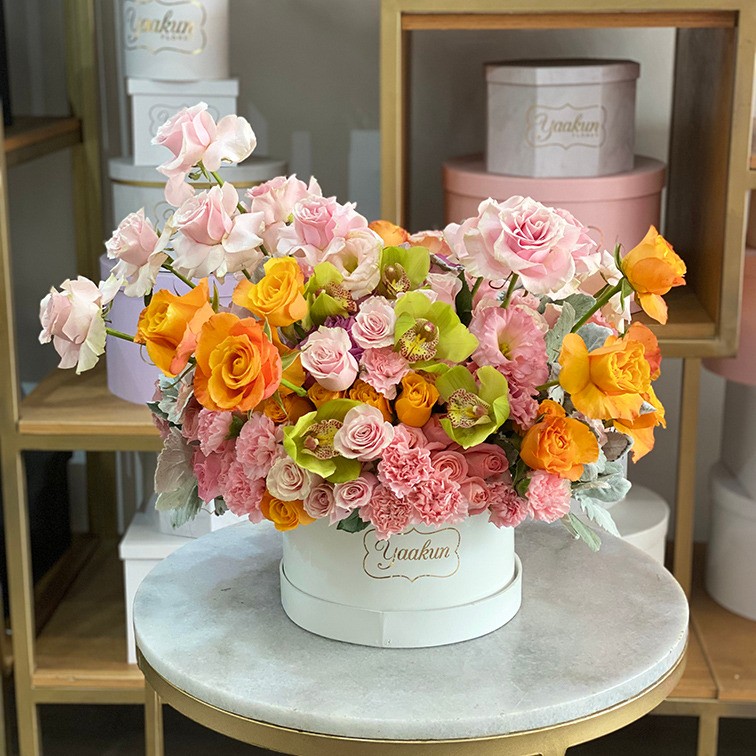 Caja chica circular blanco con rosa clavel y lisianthus rosa y toques de cymbidium verde