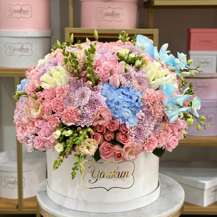 Caja circular blanca con 150 rosas, clavel roxanas, peritos y toques de hortencia y orquidea azul