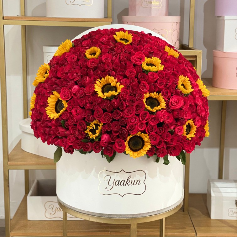 Caja circular blanca con 500 rosas rojas y toques de girasol