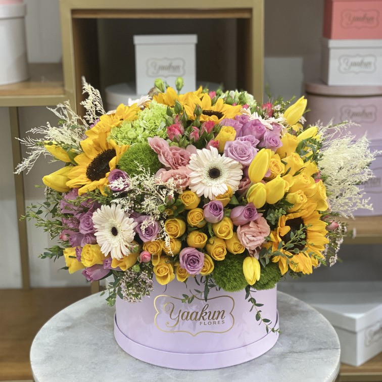 Caja circular lila con 100 rosas,girasoles tulipanes y caspia blanca