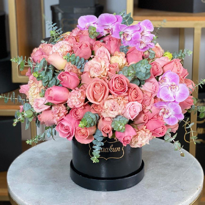 Caja circular negra con 150 rosas rositas, lisianthus y phalenosis lila