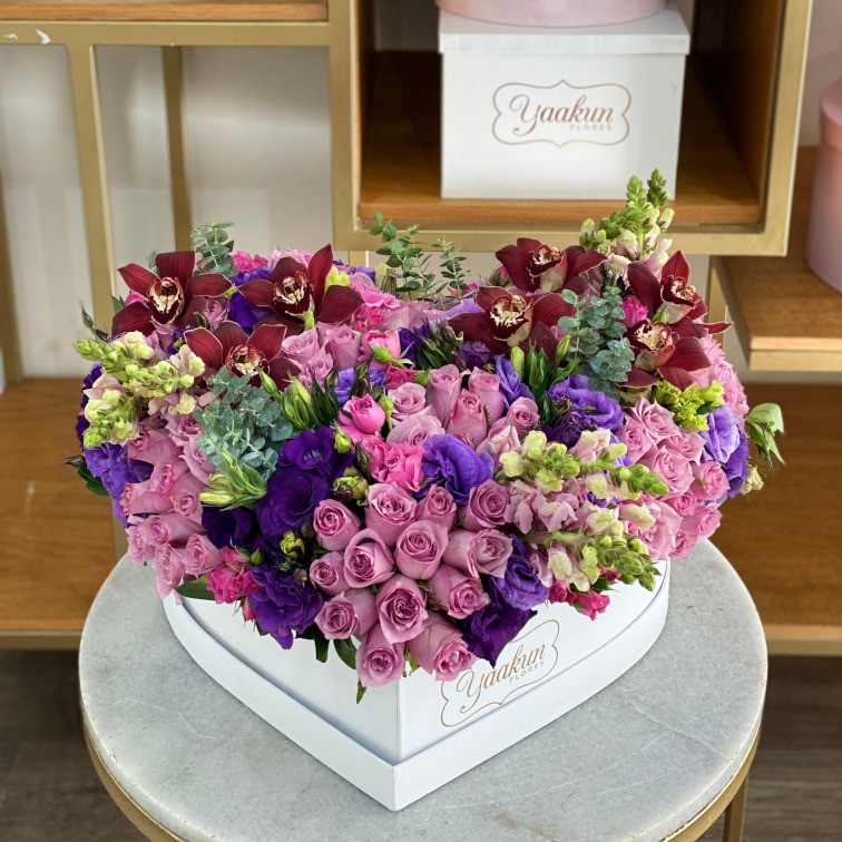 Caja corazón blanca c/t con 125 rosas lilas, tulipanes, lisianthus perritos, baby rose y toques de orquídea cymbidium tinta