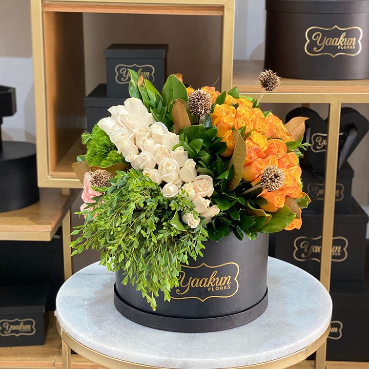 Caja negra circular con rosas naranjas y blancas