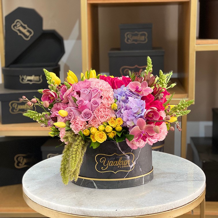 Caja ovalada negra con 25 rosas, tulipanes, ortencias, lisianthus y follajes finos
