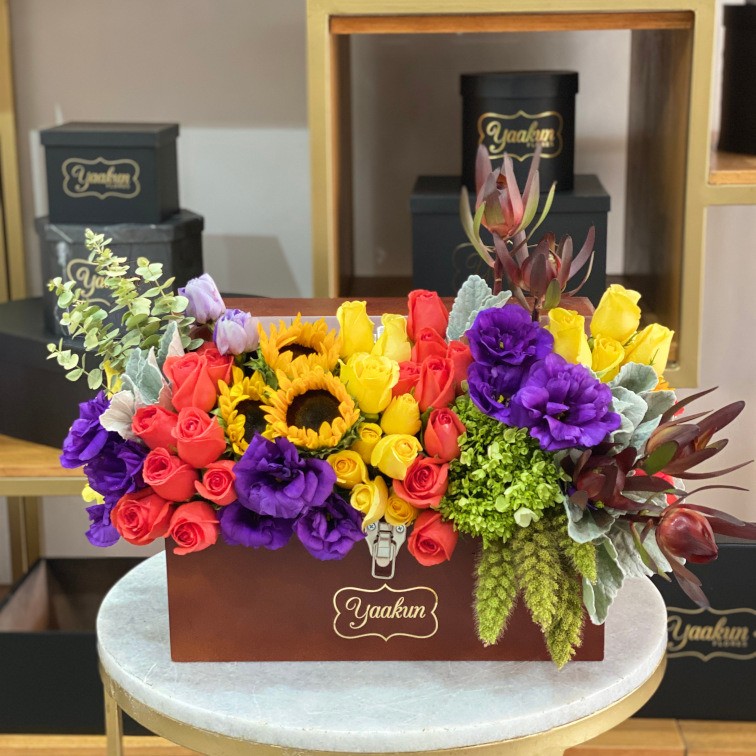 Cofre caoba mediano con 50 rosas, girasoles, lisianthus,safari y dólar