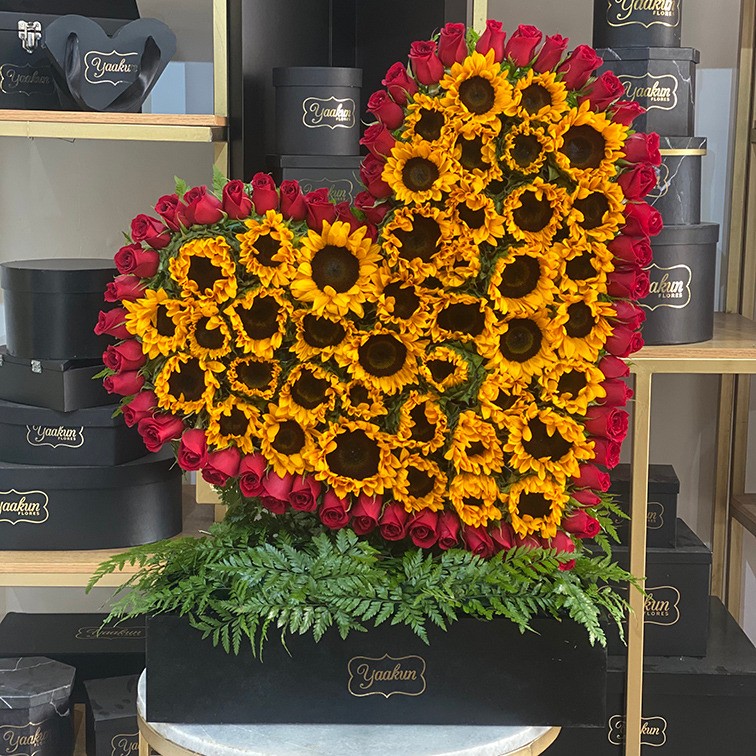Corazón en escultura inclinado grande de girasoles y contorno rosa roja en caja negra