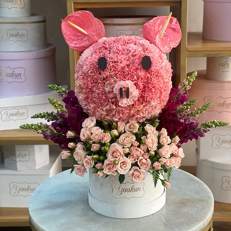 Escultura cabeza de puerco en caja circular blanca con clavel y anturios