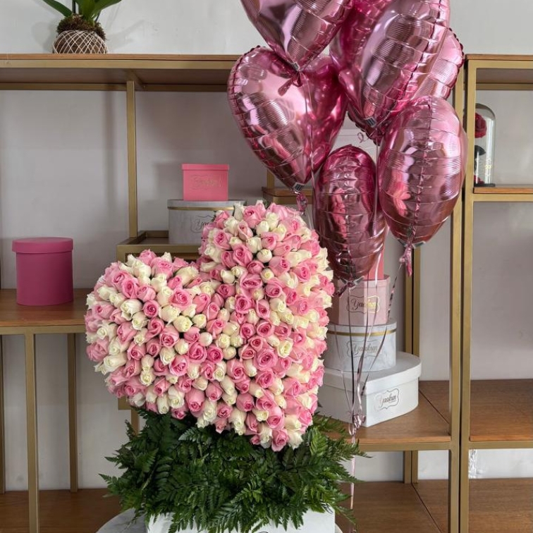 Escultura de 250 rosas rositas y blancas en forma de corazón inclinado en caja blanca y 6 globos de corazón rositas
