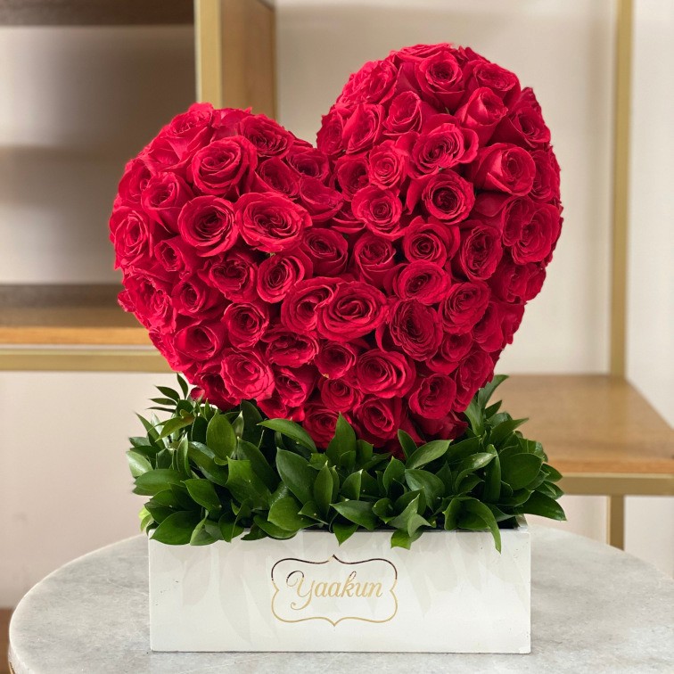 Escultura de corazón inclinado de 100 rosas rojas en caja blanca