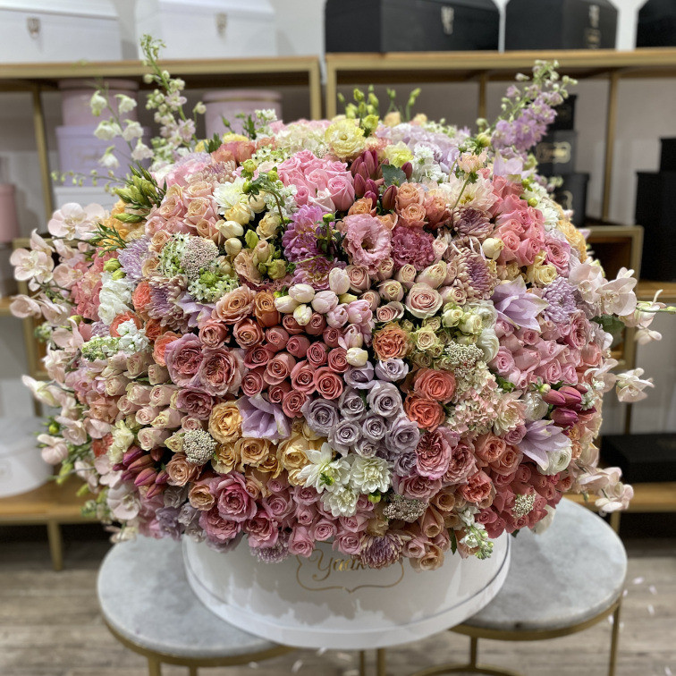 Maxi caja circular blanca con 700 rosas en tonos rositas, rosas inglesas,lisianthus, delfinio rosas, y orquídeas phalenosis rositas