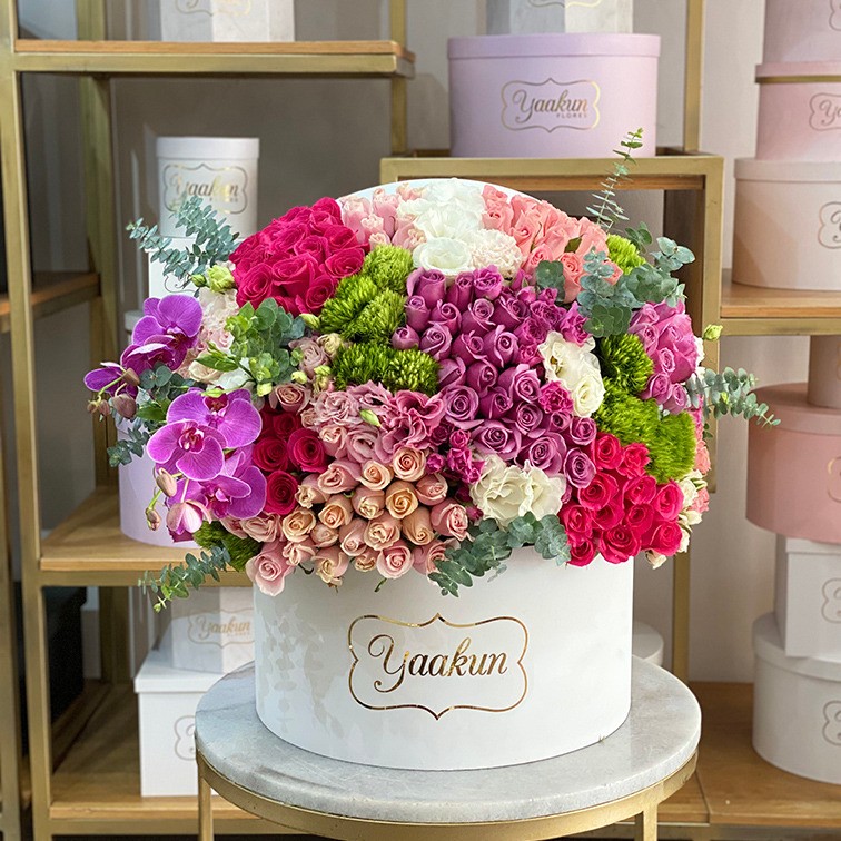 Media esfera en caja blanca con tonos rosas y fucsia y follajes finos