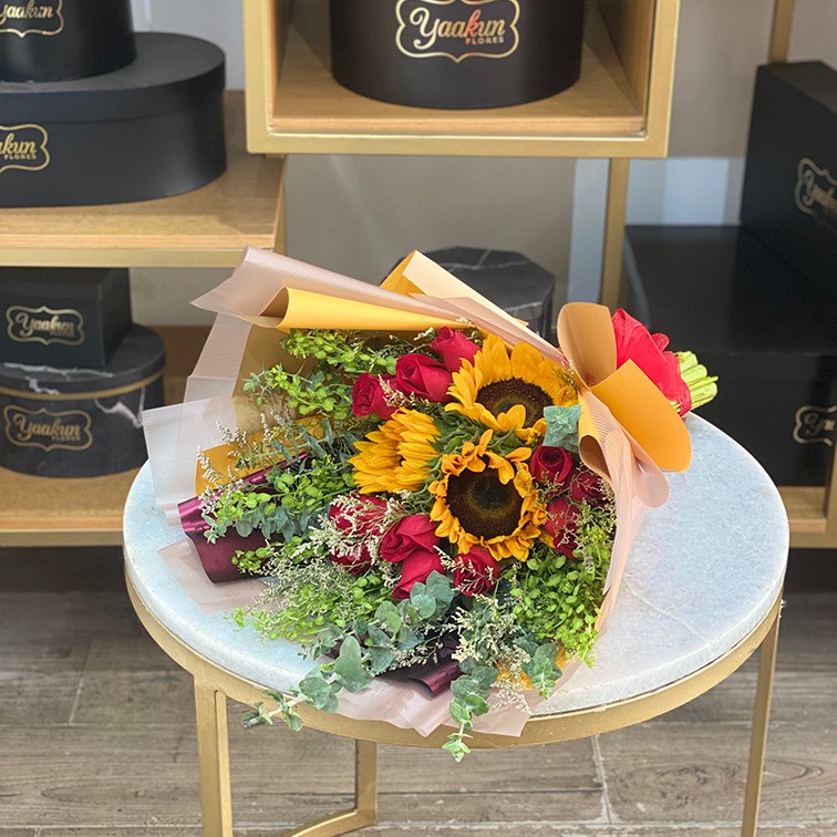 Ramo de 12 rosas y 3 girasoles con follajes y papel celofan
