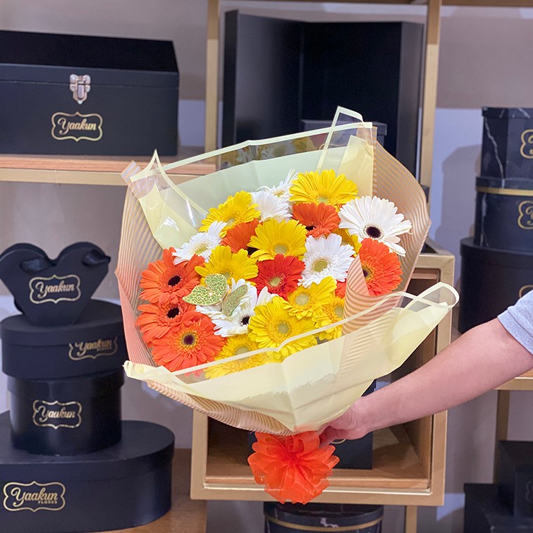 Ramo de 36 gerberas amarillas, naranjas y blancas con papel celofán y una mariposa
